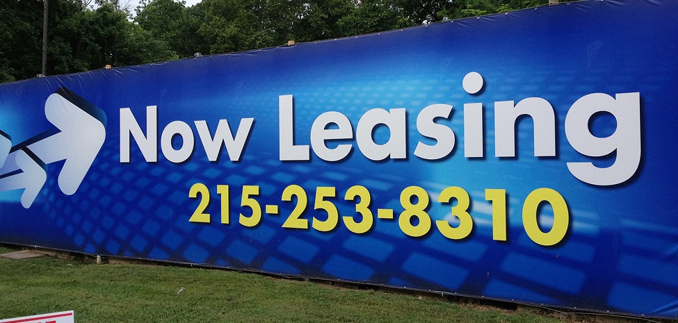 blue vinyl banner that says now leasing in white text and phone number in yellow text
